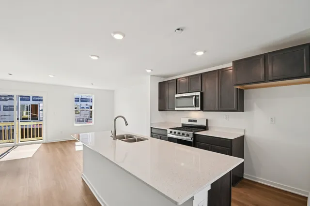 a large kitchen with stainless steel appliances a sink a stove and a refrigerator