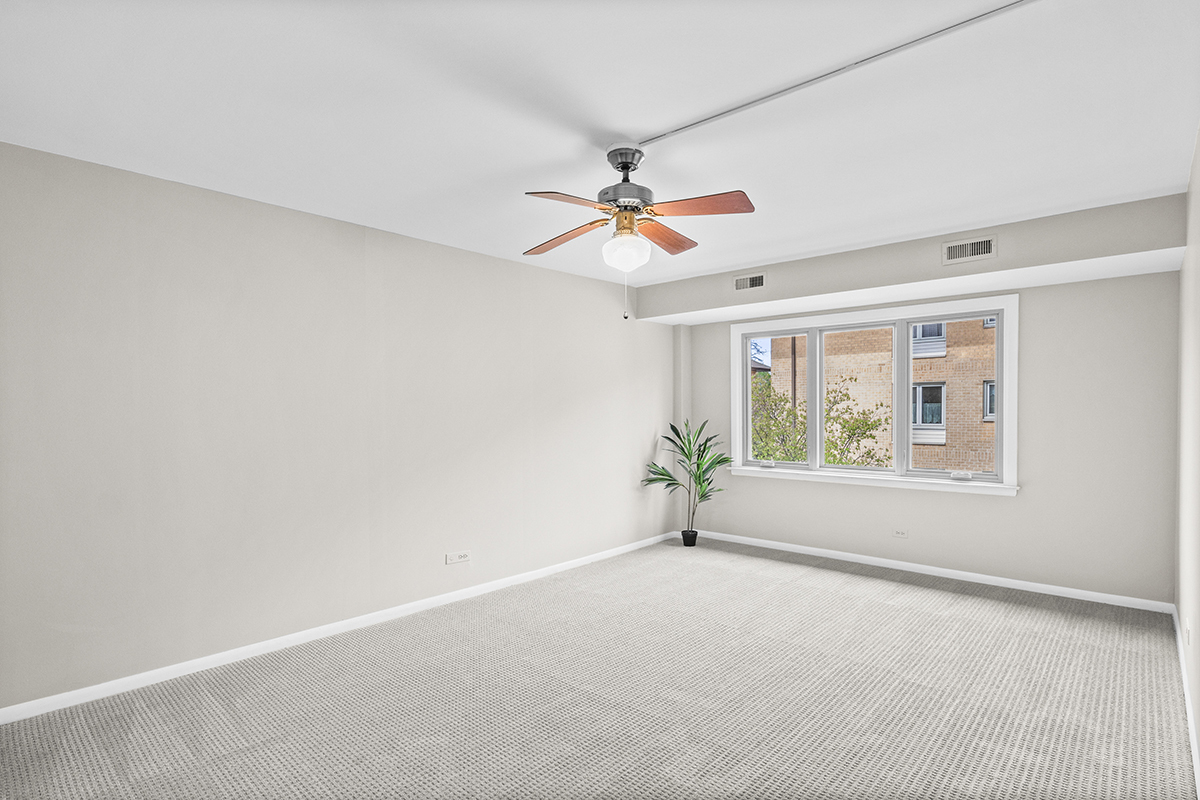 2420 West Talcott Road, Unit 211 Park Ridge, IL 60068 - Photo 7 of 28 an empty room with windows and chandelier fan