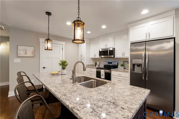 a kitchen with stainless steel appliances granite countertop a sink a stove a refrigerator a washer dryer and white cabinets