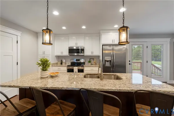 a kitchen with granite countertop a sink stainless steel appliances and white cabinets