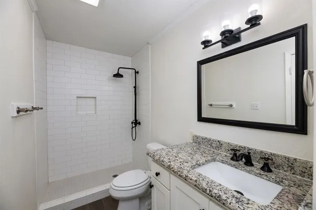 a bathroom with a granite countertop sink a toilet and a mirror