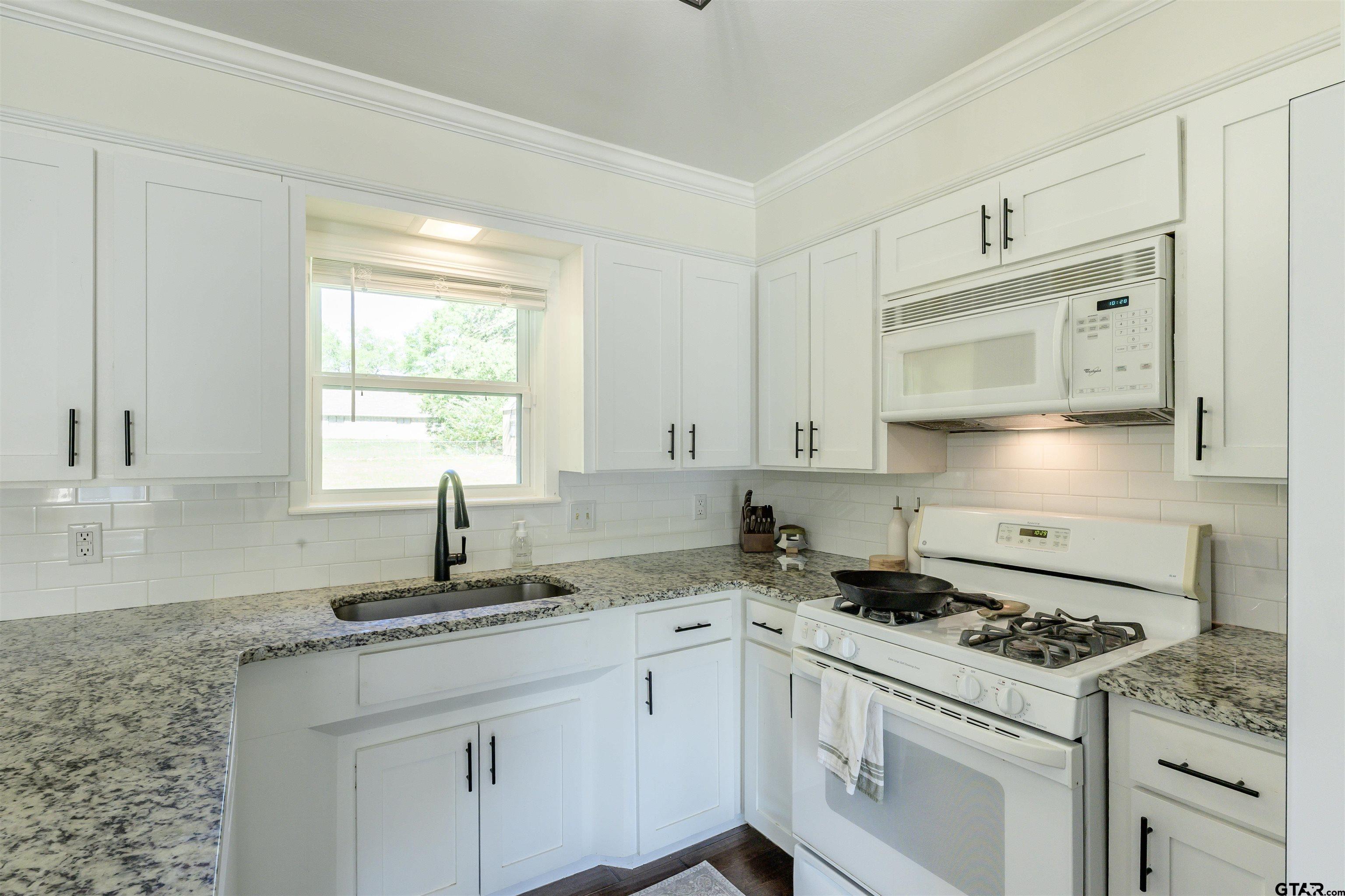 5921 Springbrook Drive Tyler, TX 75707 - Photo 9 of 39 a kitchen with granite countertop a sink cabinets stainless steel appliances and a window