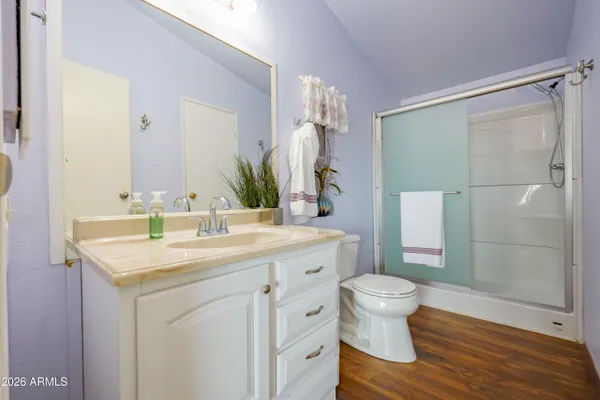 a bathroom with a granite countertop sink a toilet a mirror and shower