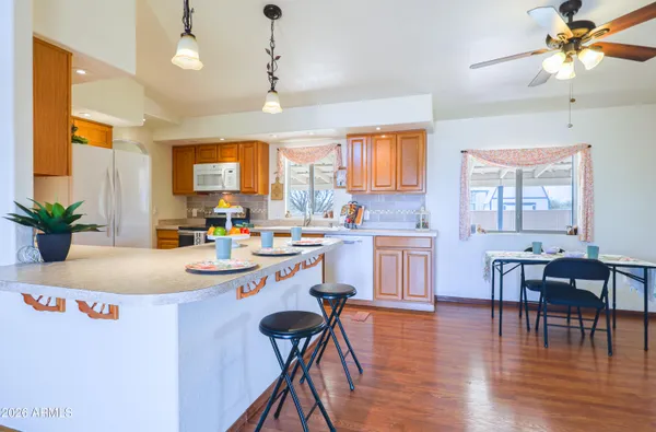 a kitchen with stainless steel appliances kitchen island granite countertop a stove a sink a dining table and chairs with wooden floor