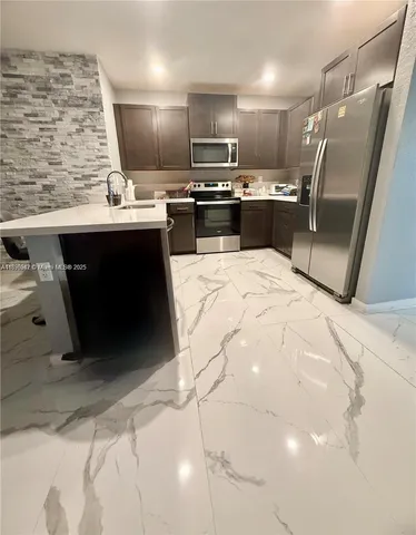 a kitchen with kitchen island stainless steel appliances a sink stove and refrigerator