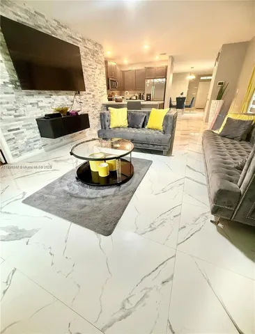 a living room with patio furniture and a flat screen tv