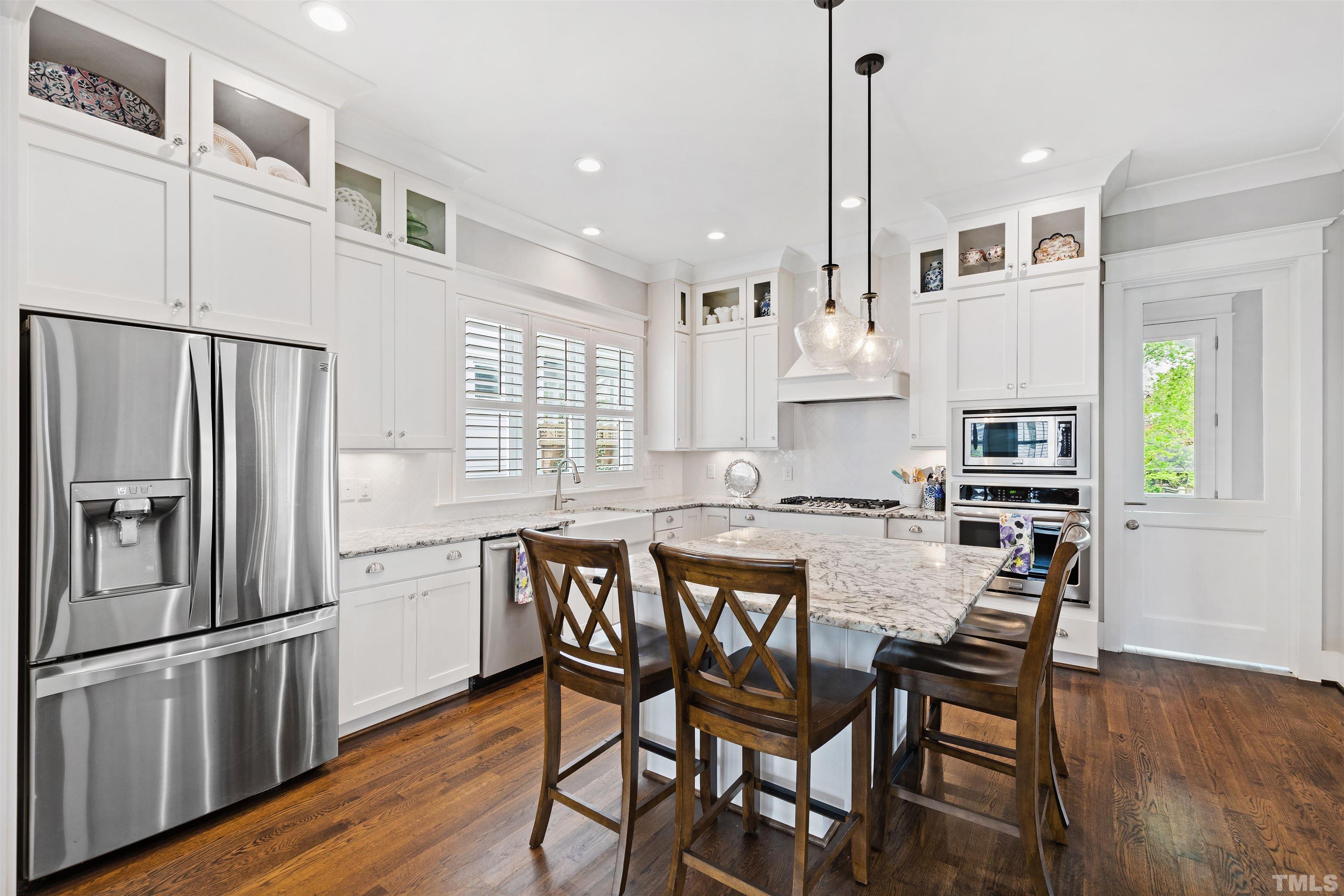 721 Virginia Avenue Raleigh, NC 27604 - Photo 12 of 49 a kitchen with stainless steel appliances granite countertop a dining table chairs refrigerator and microwave