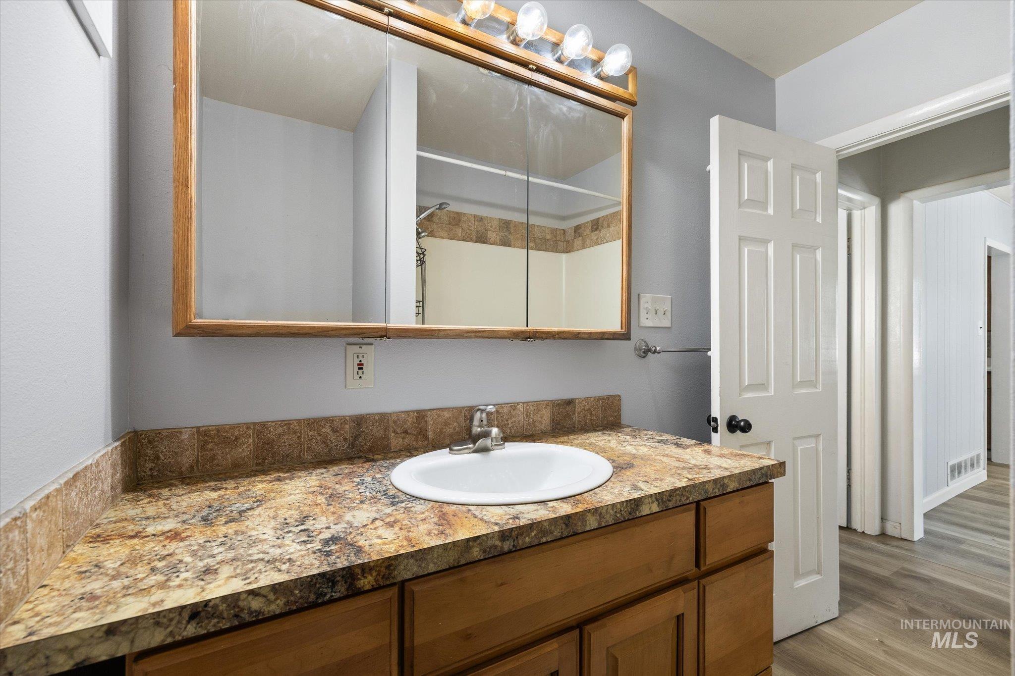 918 West 3rd Street Weiser, ID 83672 - Photo 11 of 36 Bathroom vanity featuring a built-in sink, wood-finish cabinetry, and a patterned countertop with a matching backsplash