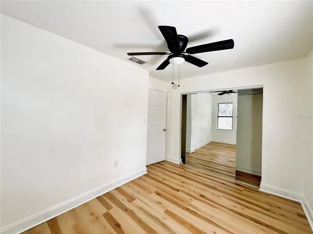 a view of a room with wooden floor and ceiling fan