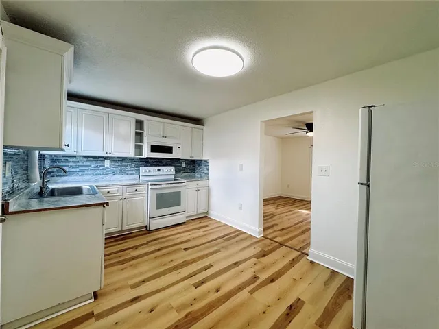a kitchen with granite countertop white cabinets and white appliances