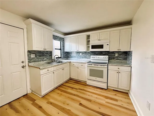 a kitchen with granite countertop white cabinets and white appliances