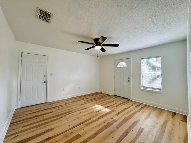 a view of empty room with wooden floor and fan