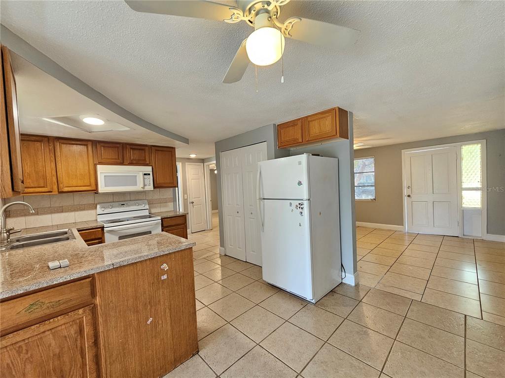 9210 Pegasus Avenue Port Richey, FL 34668 - Photo 6 of 19 a kitchen with a refrigerator a stove cabinets and living room view