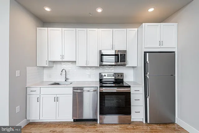 a kitchen with white cabinets sink and stainless steel appliances