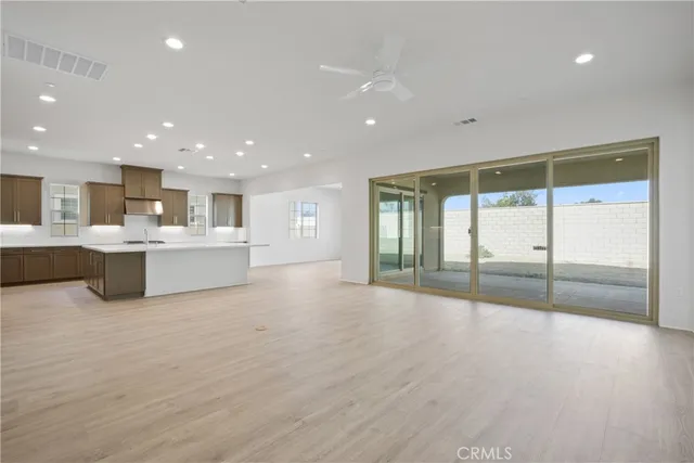a view of an empty room with wooden floor and windows
