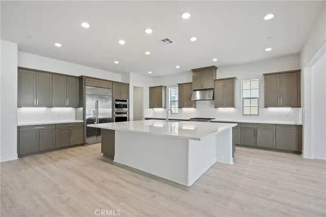 a large kitchen with kitchen island a sink a counter top stainless steel appliances and cabinets