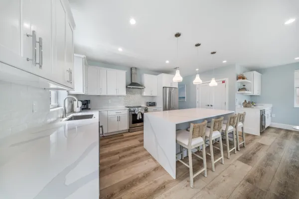 a kitchen with stainless steel appliances kitchen island granite countertop a table chairs sink and cabinets