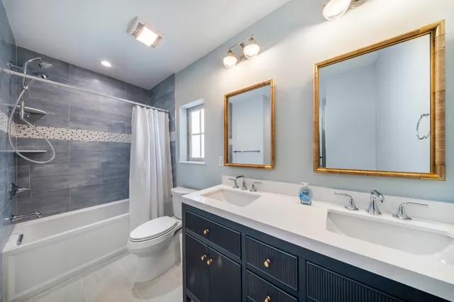 a bathroom with a double vanity sink toilet mirror and shower