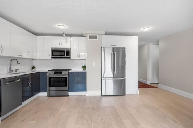 a kitchen with kitchen island a refrigerator and a stove top oven