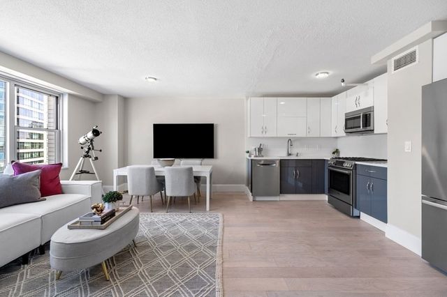 a living room with furniture a flat screen tv and kitchen view