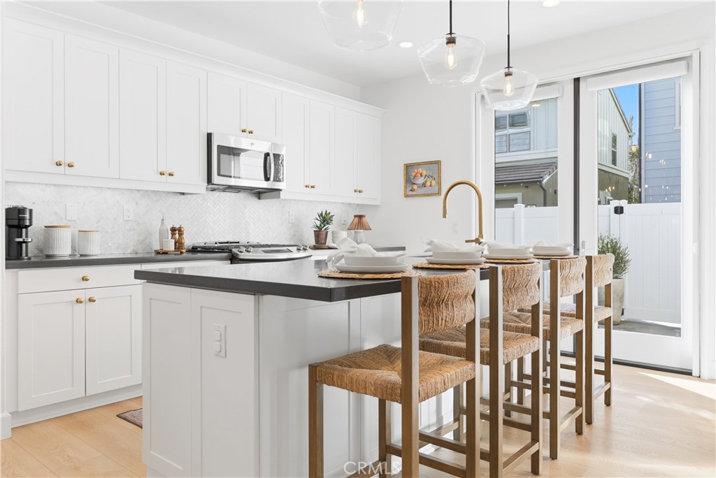 a kitchen with granite countertop a table chairs stove and white cabinets