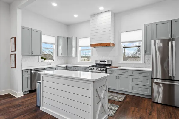 a kitchen with stainless steel appliances granite countertop a dining table chairs stove refrigerator and cabinets