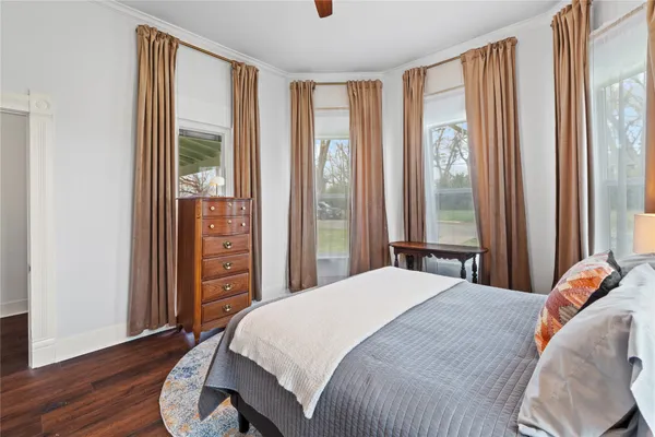 a bedroom with a bed and a large window with wooden floor