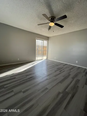 an empty room with wooden floor fan and windows