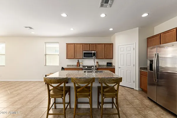 a kitchen with stainless steel appliances granite countertop a table chairs sink refrigerator and microwave