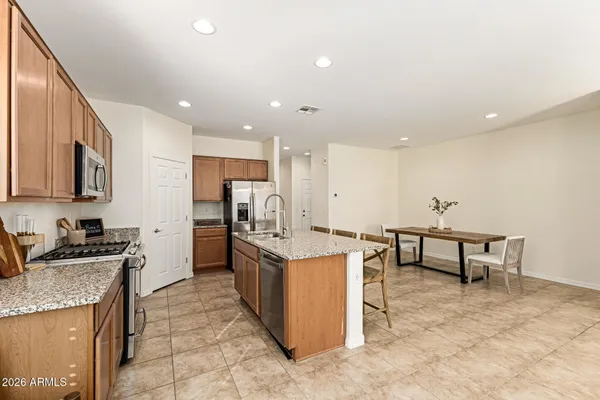 a kitchen with stainless steel appliances granite countertop a stove top oven a sink a dining table and chairs
