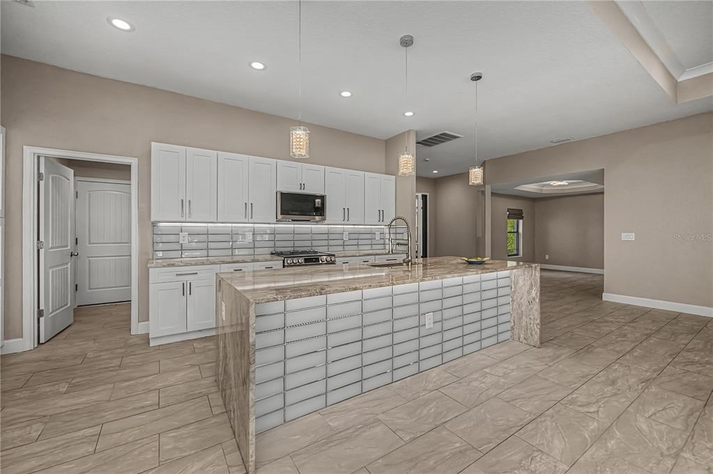 159 April Road Rotonda West, FL 33947 - Photo 18 of 73 a large white kitchen with kitchen island a sink stainless steel appliances and cabinets