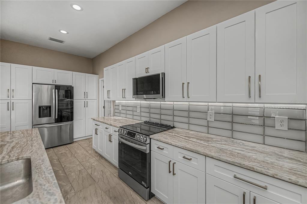159 April Road Rotonda West, FL 33947 - Photo 21 of 73 a kitchen with granite countertop a sink stove and refrigerator