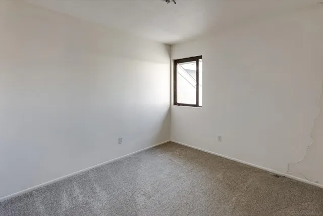 a view of an empty room with closet and a window