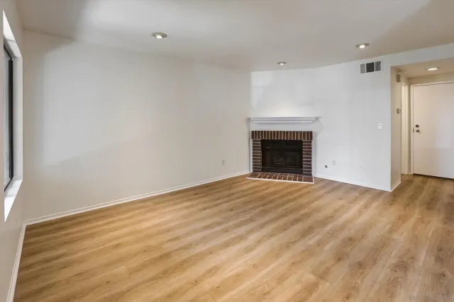 a view of empty room with wooden floor and fireplace