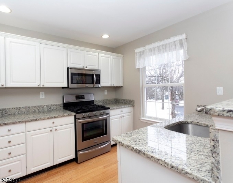 3 Minuteman Court Bernards, NJ 07920 - Photo 7 of 12 a kitchen with granite countertop white cabinets and a stove with wooden floor