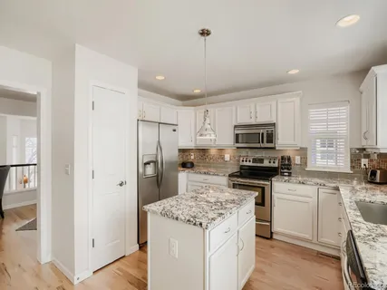 a kitchen with a sink a stove a refrigerator a center island and cabinets