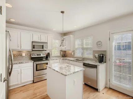 a kitchen with granite countertop appliances cabinets and a wooden floor