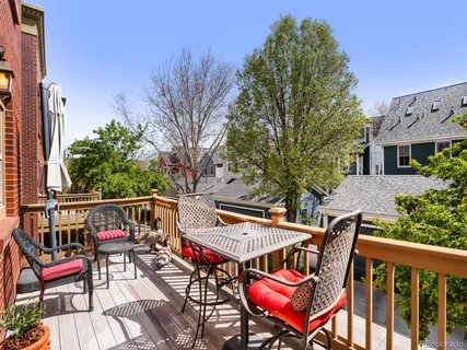 a roof deck with a table and chairs with wooden floor and fence