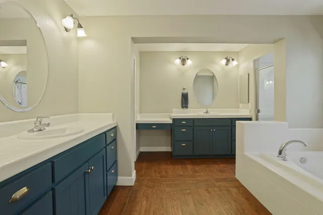 a bathroom with a double vanity sink mirror and bathtub