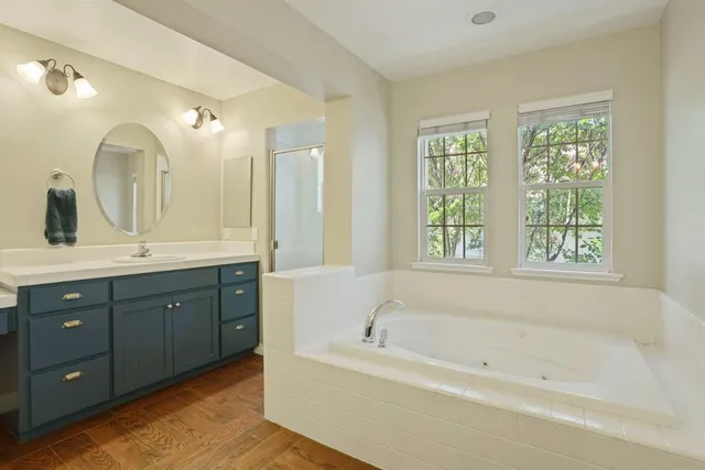 a bathroom with a tub a sink double vanity and a large mirror