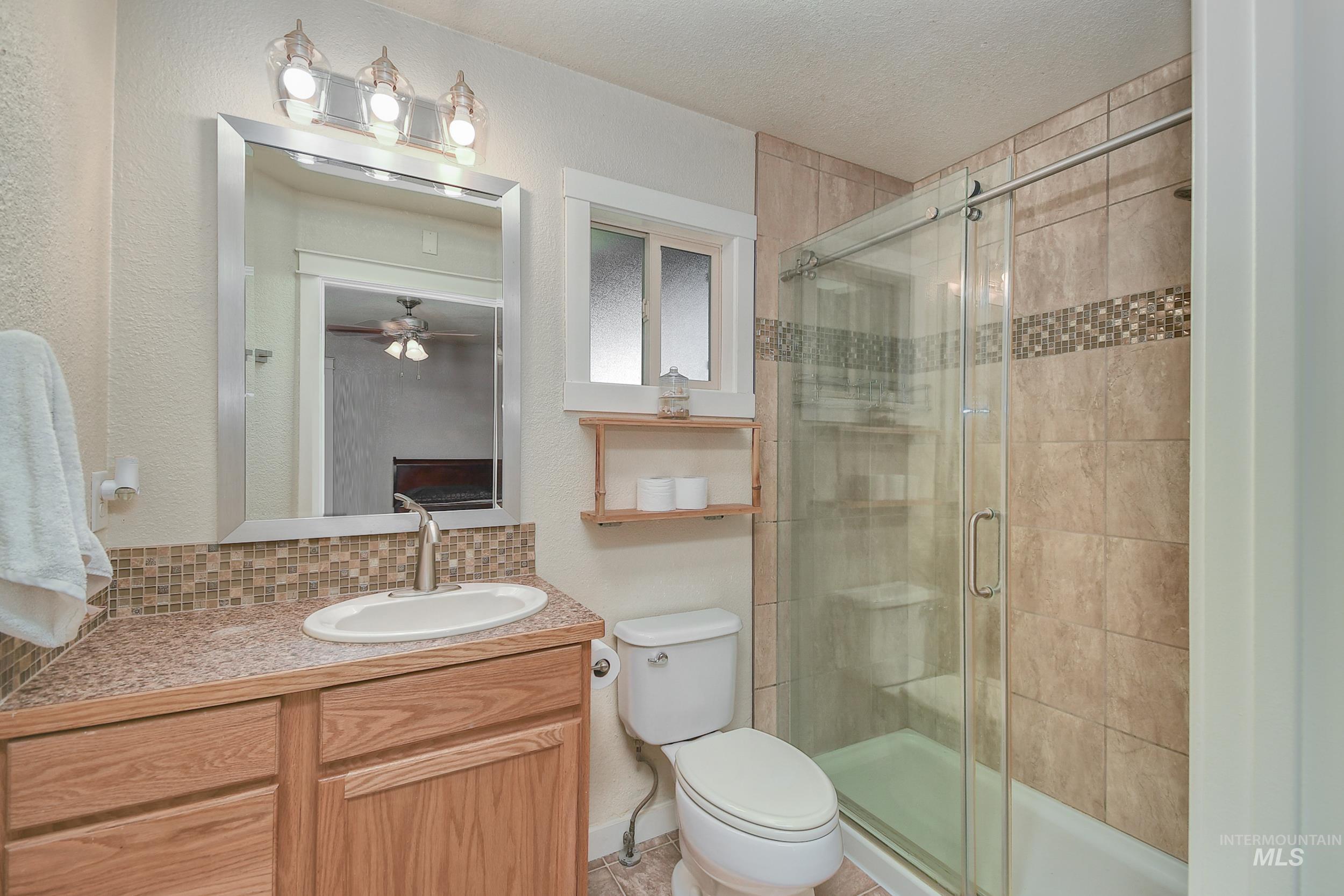1108 East Ustick Road Caldwell, ID 83607 - Photo 24 of 30 Bathroom featuring a wood-finish vanity with a surface-mount sink, a tiled countertop, and a mosaic tile backsplash