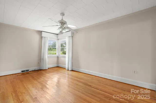 an empty room with wooden floor cabinet and windows