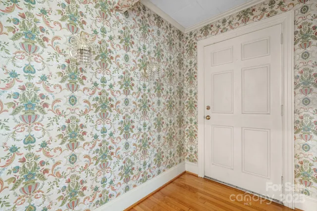 an empty room with wooden floor chandelier fan and windows