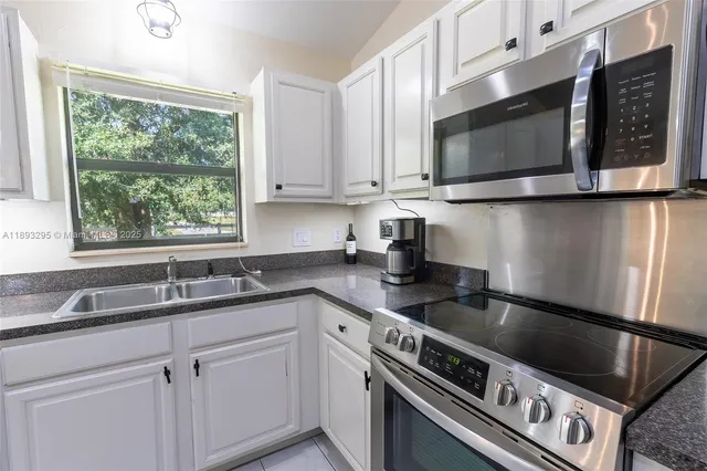 a kitchen with granite countertop white cabinets stainless steel appliances and a sink