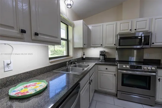 a kitchen with granite countertop a sink a stove and microwave
