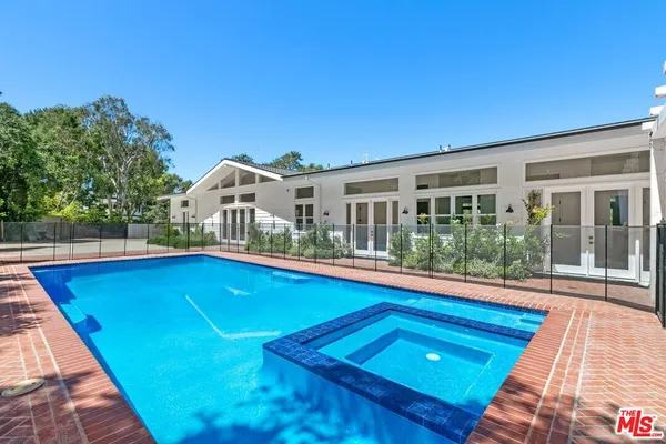 a view of a swimming pool with a patio and a backyard