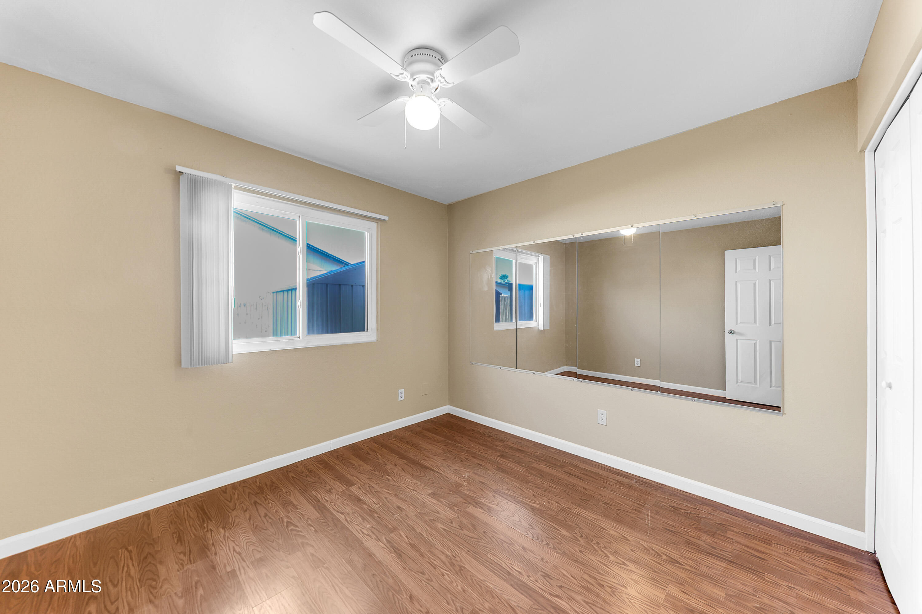 4723 East Vineyard Road Phoenix, AZ 85042 - Photo 22 of 27 a view of an empty room with window and wooden floor