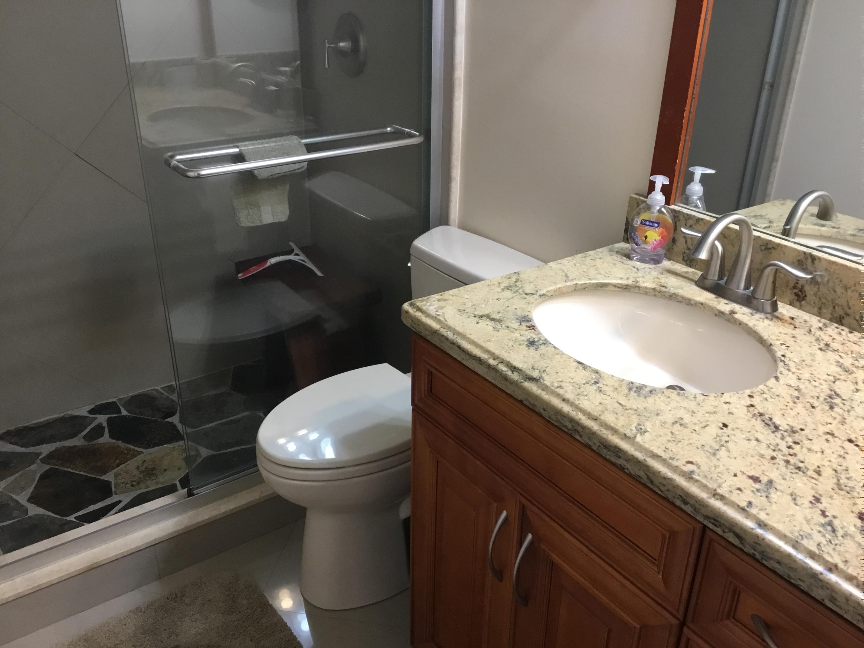 906 Southwest 9th St Circle, Unit 106 Boca Raton, FL 33486 - Photo 18 of 26 a bathroom with a granite countertop sink a toilet and a mirror