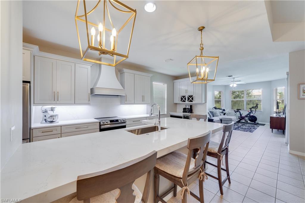 20599 Ardore Lane Estero, FL 33928 - Photo 5 of 34 a kitchen with stainless steel appliances granite countertop a stove a refrigerator a sink a dining table and chairs with wooden floor