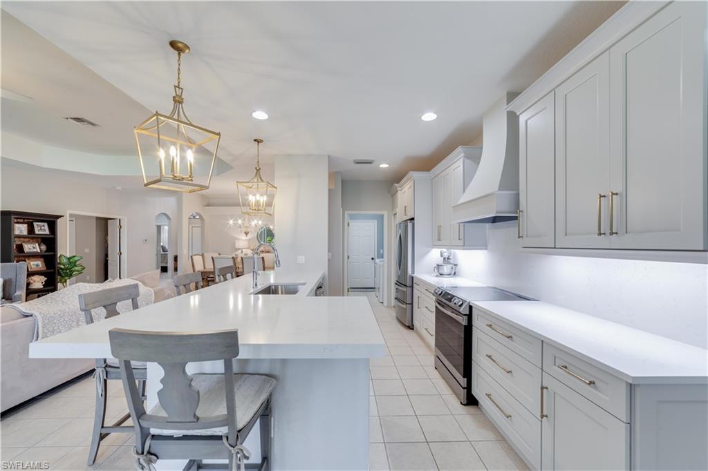 20599 Ardore Lane Estero, FL 33928 - Photo 7 of 34 a large kitchen with granite countertop a stove a sink a dining table and chairs